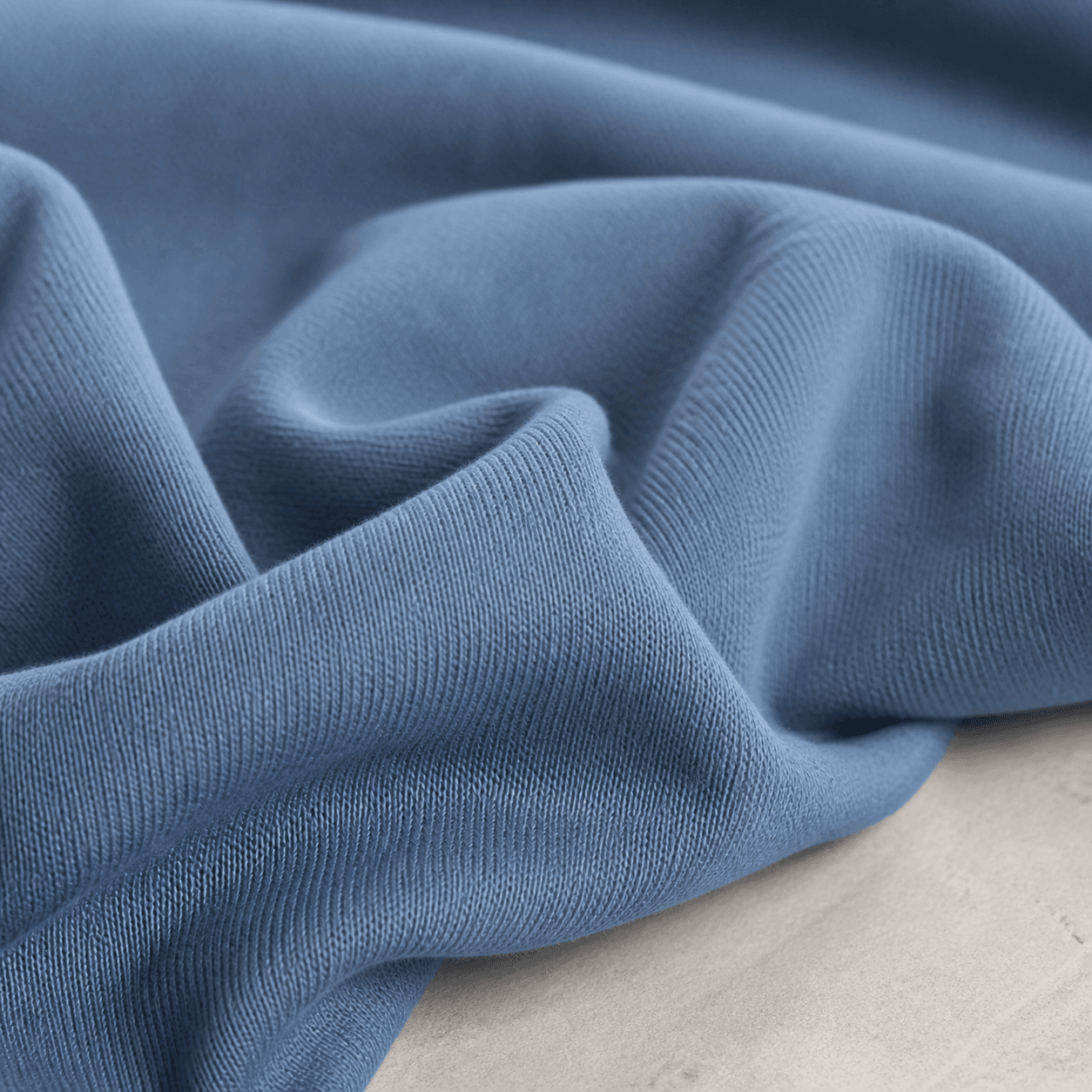 Macro view of soft washed-blue cotton jersey in rolling folds