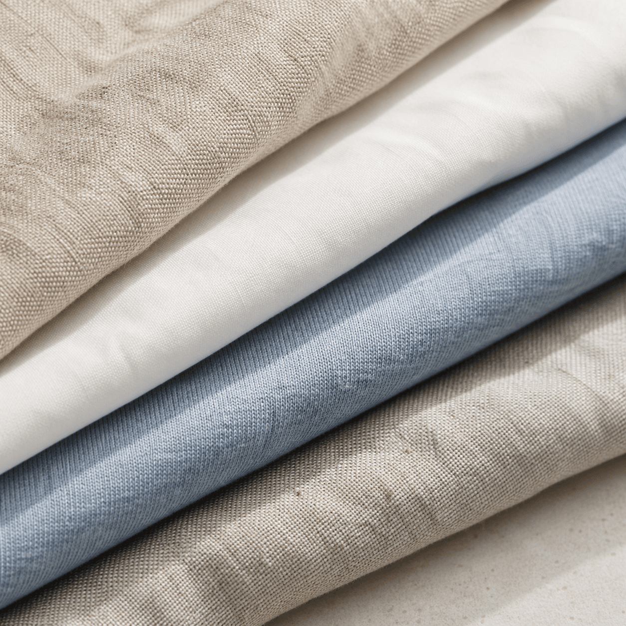 Close view of soft washed-blue cotton jersey beside natural linen and cotton poplin